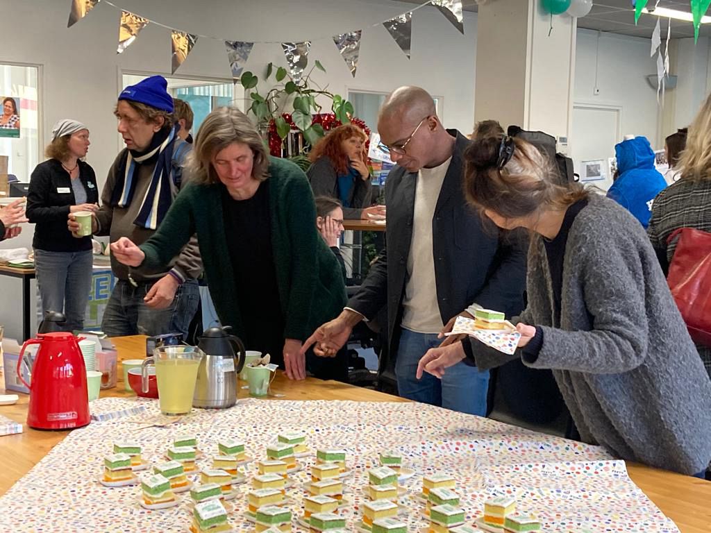 Mensen staan bij de tafel met koffie en taart